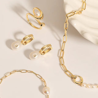 Gold jewellery set with rings and a bracelet on a beige background