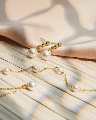 Gold and pearl jewelry set on a soft fabric background