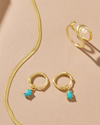 Gold jewelry set with turquoise stones on a beige background