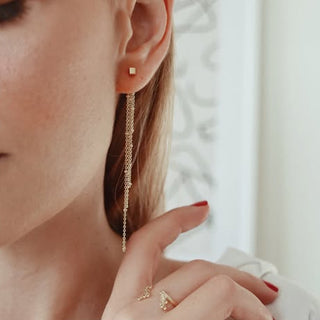 Close-up of a woman wearing gold earrings and rings with a blurred background