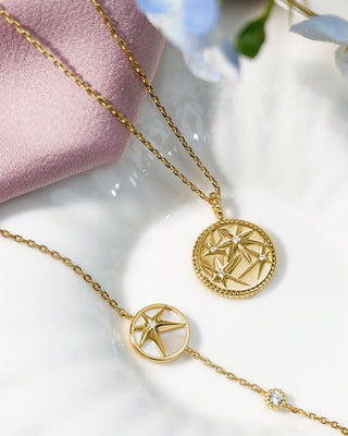 Gold necklaces with star-shaped pendants on a white surface.