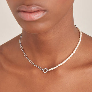 Pearl necklace with silver chain on a person against a neutral background