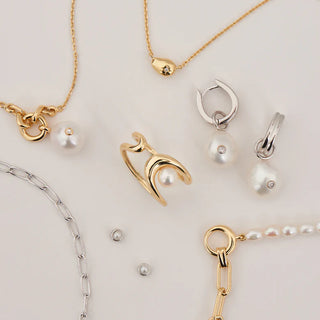 Collection of gold and silver jewellery with pearls on a light background