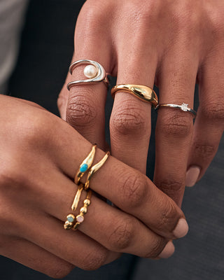 Close-up of hands wearing multiple gold rings with various designs.