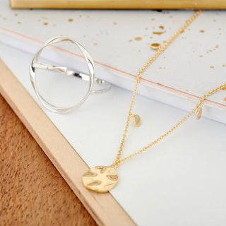 Gold necklace with a heart pendant on a white surface