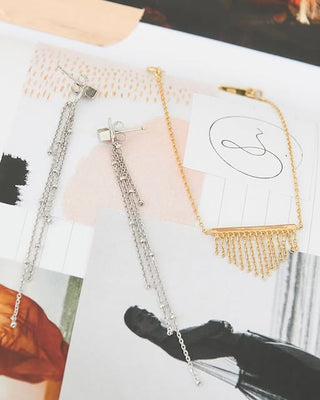 Two necklaces, one silver and one gold, on a magazine page.