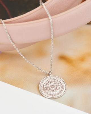 Silver necklace with a round pendant on a person's neck