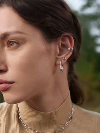 Close-up of a woman wearing silver earrings and a necklace with a blurred natural background