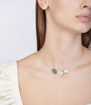 Necklace with three circular pendants on a plain background