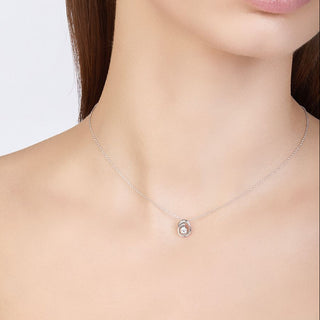 Necklace with a small round pendant worn by a person on a plain background