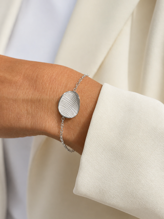 White Gold textured disc bracelet on a wrist with a neutral background
