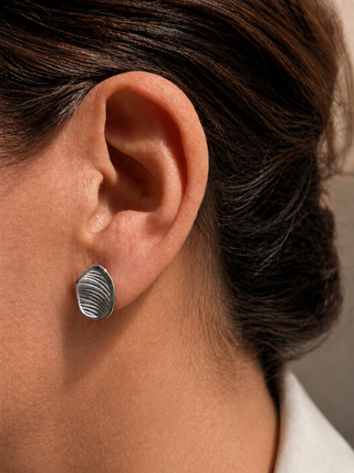 Close-up of an ear wearing a silver earring with a blurred background
