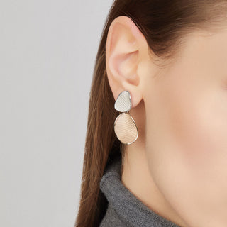 Close-up of a person wearing gold earrings with a plain background