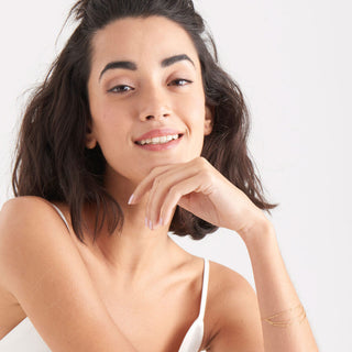 Woman with a soft smile and hand under her chin on a plain background