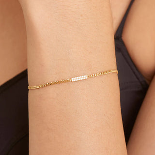 Gold bracelet on a person's wrist with a neutral background