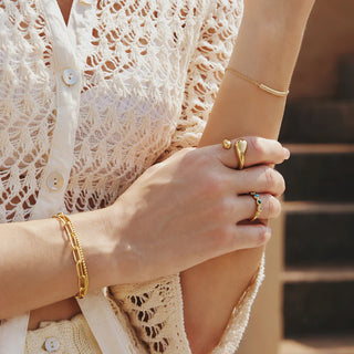 Close-up of a person wearing gold ania haie jewellery with a blurred background