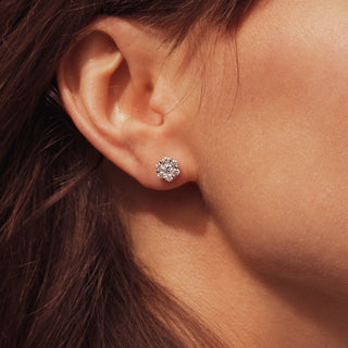 Close-up of an ear wearing a diamond earring with hair partially covering the side.