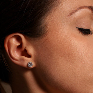 Close-up of an ear wearing a diamond earring with a blurred background
