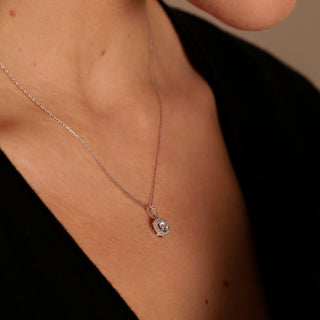 Necklace with a pendant on a person wearing a black top against a neutral background