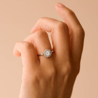 Hand wearing a diamond ring on a beige background