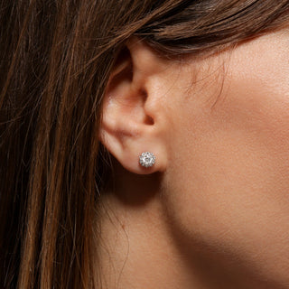 Close-up of an ear wearing a diamond earring with hair partially covering the face.