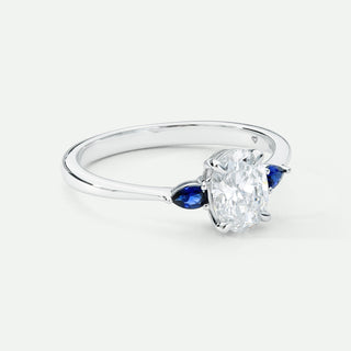 White Gold ring with a large diamond and smaller blue gemstones on a white background