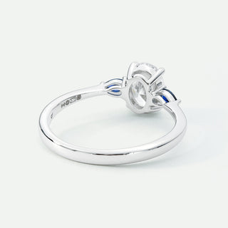 Silver ring with a diamond and blue gemstones on a white background