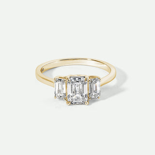 Gold ring with three emerald-cut diamonds on a white background