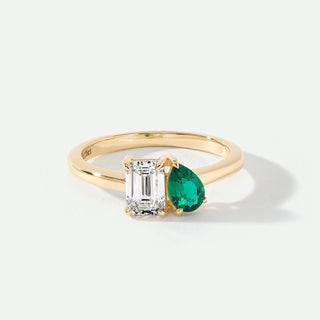 Gold ring with emerald and diamond on a white background