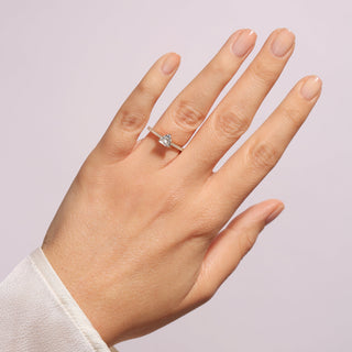 Hand wearing a diamond ring on a light purple background