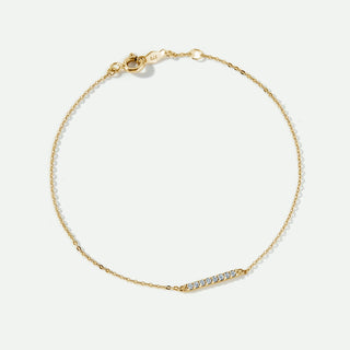 Gold bracelet with small diamonds on a light beige background