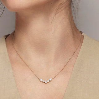 Necklace with five small stones worn by a person against a neutral background