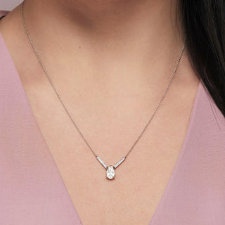 Necklace with a teardrop-shaped pendant worn by a person against a pink background