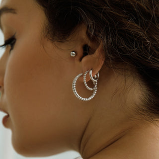 Close-up of a person wearing silver hoop earrings with a blurred background