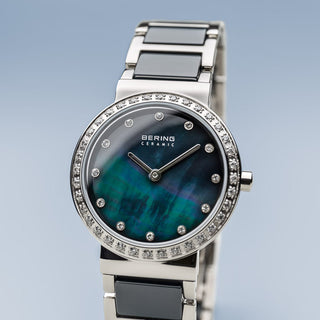 Silver watch with a blue face and diamond accents on a light gray background