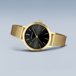 Gold watch with black face on a light gray background