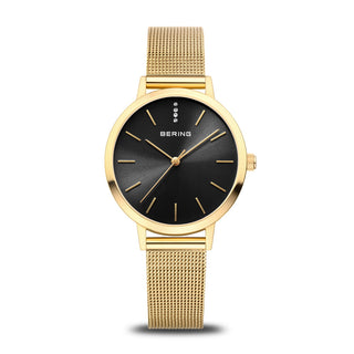 A Bering ladies watch with a gold mesh bracelet and a black dial, featuring a polished gold case and a safety clasp.