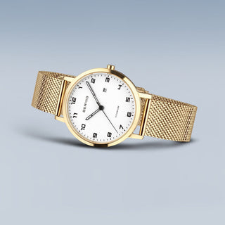 Gold watch with a white face on a light gray background