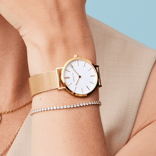 Gold watch on a wrist with a light background