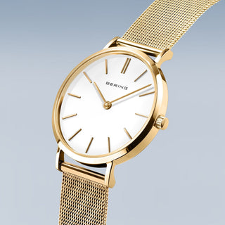 Gold watch with a white face on a light gray background