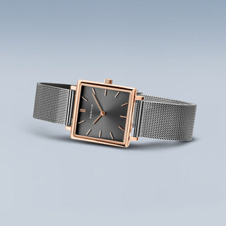 Wristwatch with rose gold case and silver mesh band on a light gray background
