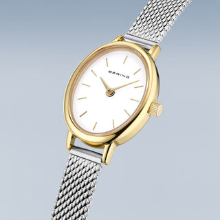 Gold and silver watch with Bering brand on a light gray background