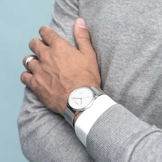 Person wearing a silver watch with a light blue background