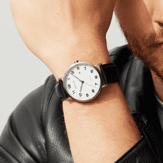 Man wearing a black wristwatch with a white face on a gray background