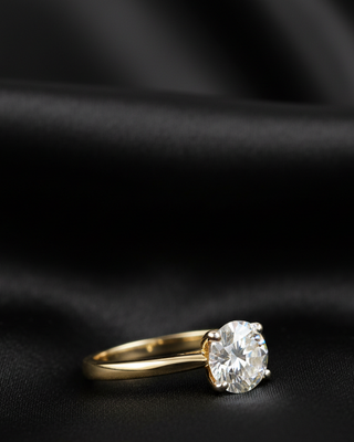 Gold ring with a diamond on a black fabric background