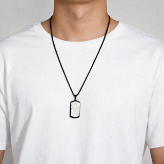 Person wearing a necklace with a black pendant on a plain background