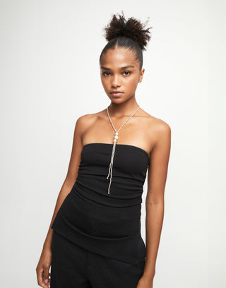 Woman wearing a black strapless dress with a necklace on a white background