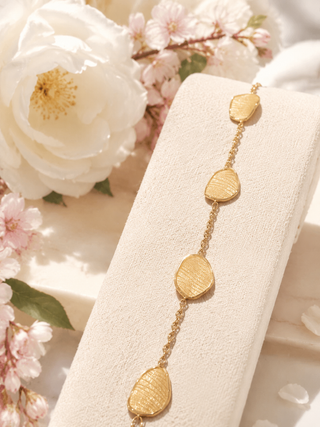 Gold bracelet on a white stand with floral background