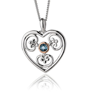 Heart-shaped silver pendant with rose gold accents and a blue gemstone on a white background