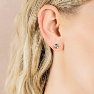 a blonde women wearing Pair of rose gold and silver earrings with clear gemstones